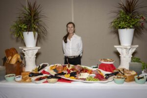 A woman standing in front of a table with many different foods.