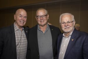 Three men standing next to each other in a room.