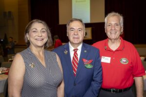 Three people standing in front of a projector screen.