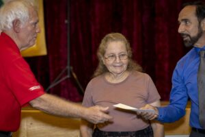 A woman is receiving an award from two men.