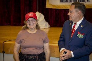 A woman wearing a red hat and smiling next to a man.