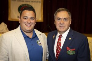 Two men standing next to each other in front of a banner.