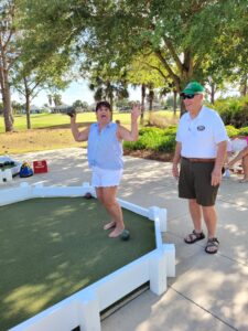 A man and woman playing mini golf on the grass.