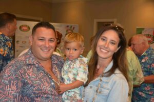 A man and woman holding a baby in front of a camera.
