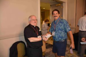Two men standing next to each other holding wii remotes.