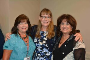 Three women standing next to each other in a room.