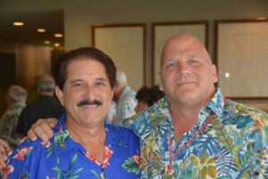 Two men in hawaiian shirts posing for a picture.