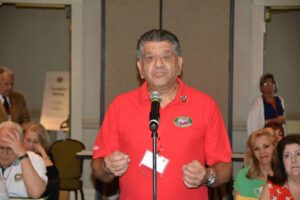 A man in red shirt speaking into microphone.