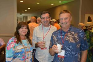 Three people are standing together holding drinks.